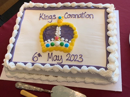 Large, white, rectangular cake with piping around the outside. The top has a crown and wording: Kings Coronation 6th May 2023.