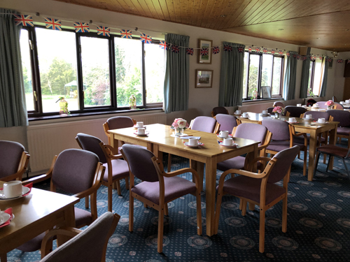 Inside the Clubhouse. Tables with centrepieces of roses and dahlias and cups and saucers. Bunting along the windows.