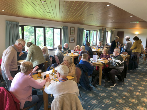 View from entrance of Clubhouse, groups of four at tables.