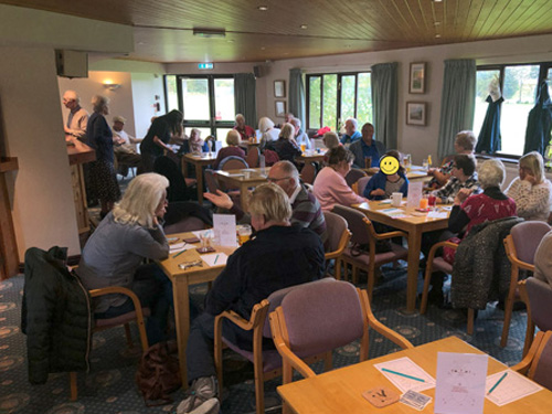 View from back of Clubhouse, groups of four people sitting at tables.