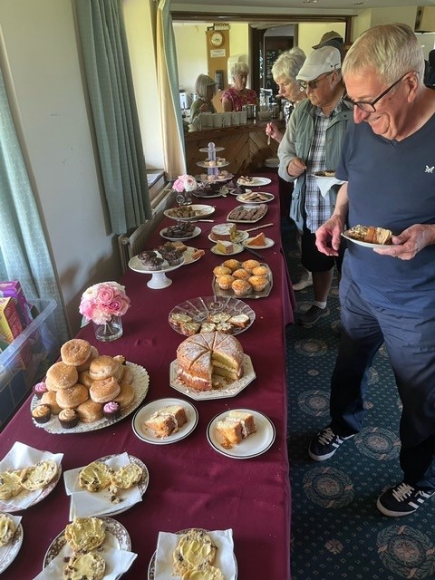 Buffet table with cakes and a line of people queuing up to get food