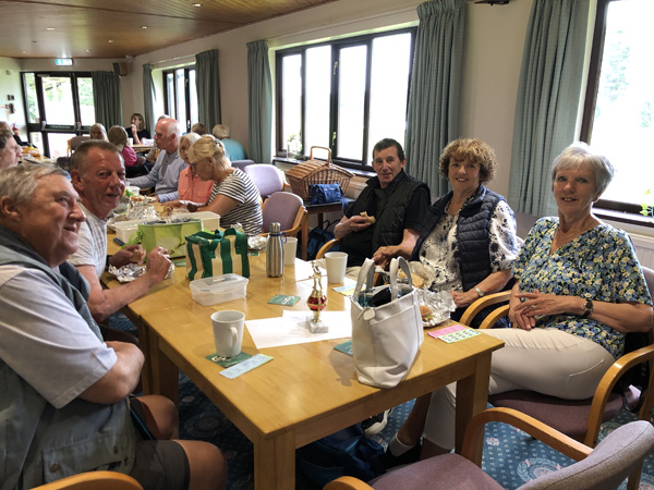 Members sitting at a long table with picnic food