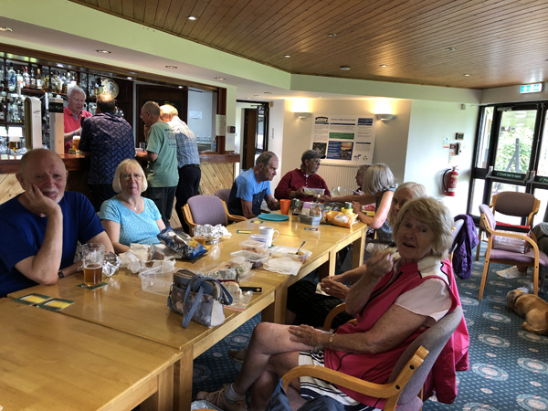 Members at the long table with picnic food. Bar in the background