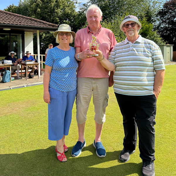 Brian and Dave T hold the trophy. Margie who hosted, stands with them