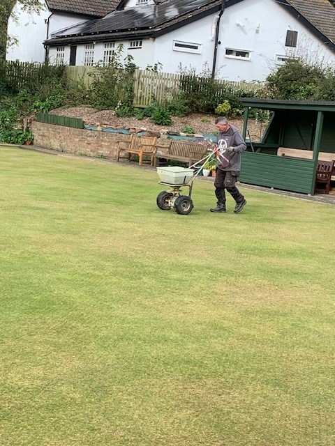 Mick applying the seed to the green