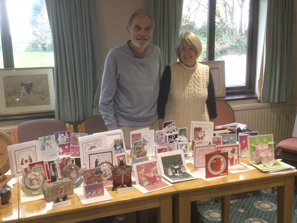 Kath and Rod behind a table filled with homemade cards.