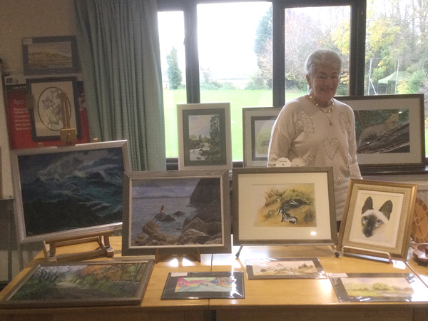 Pat standing behind a table with her paintings.