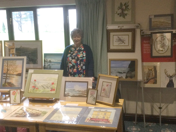 Wendy standing with her paintings.