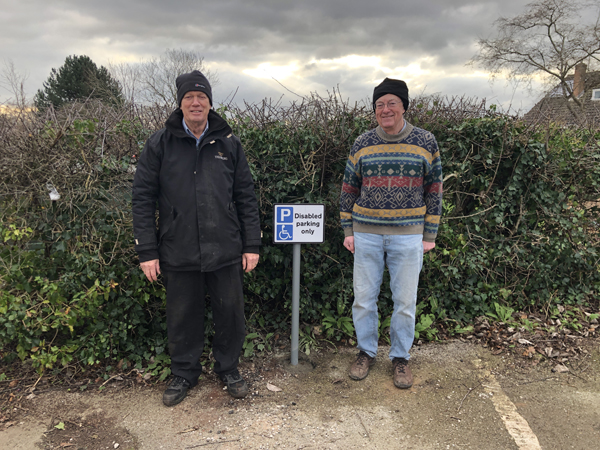 Ian and Geoff on either side of the newly installed disabled parking sign