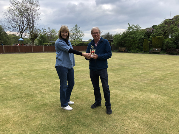 A woman and a man posing on the green with a small trophy